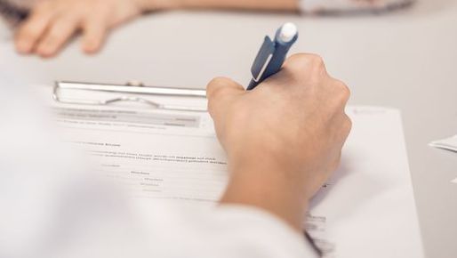 Person filles out form on a clipboard