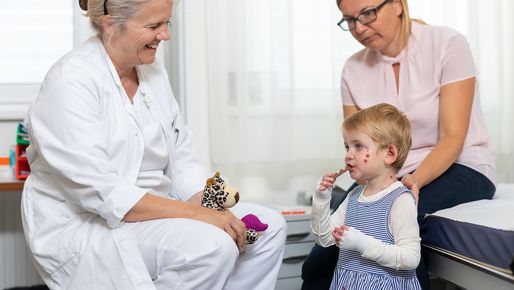 Ärztin mit Schmetterlingskind und Mutter im Behandlungsraum