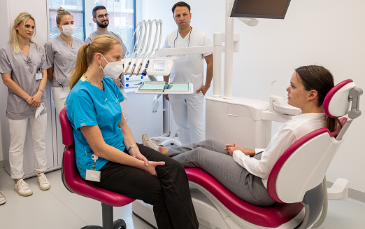 Zahnärztin mit EB-Patientin am Behandlungsstuhl, StudentInnen im Hintergrund.