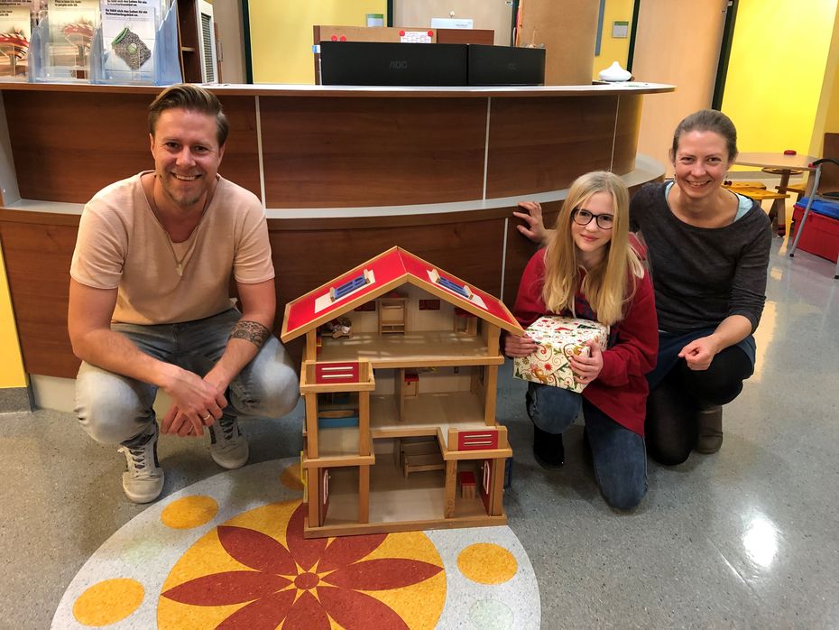 Lena hands over her doll house to employees of the EB House