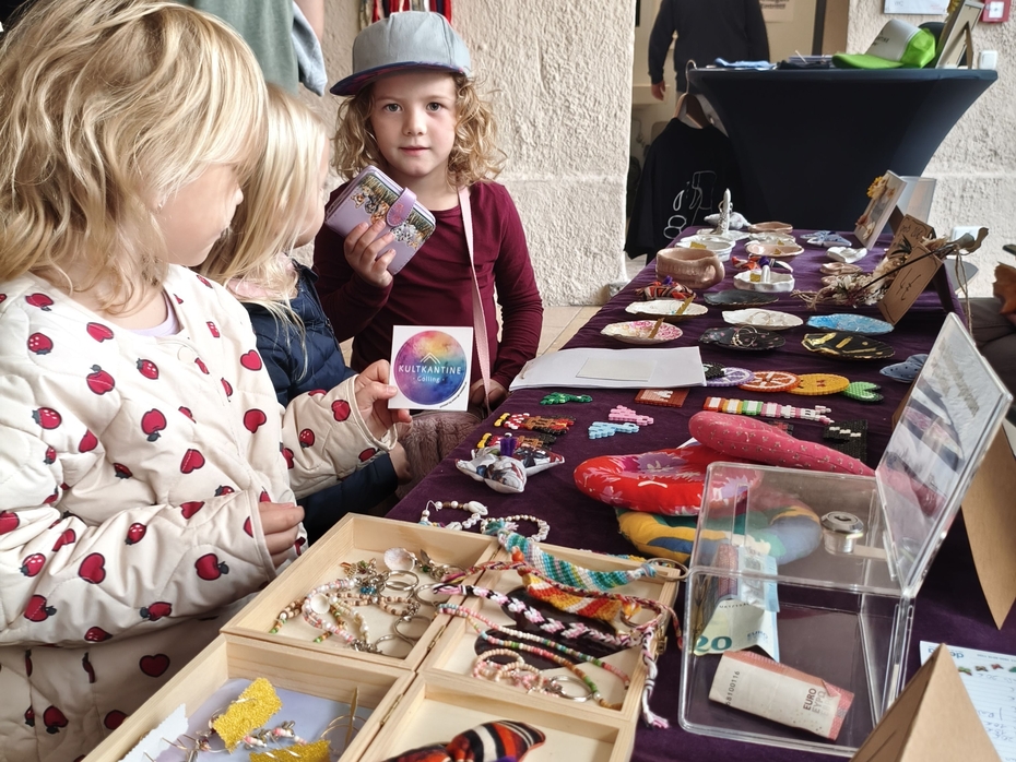 Besucherinnen beim Verkaufsstand der Kultkanteens Kinder kaufen selbstgemachten Schmuck für einen guten Zweck