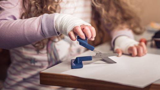 Hand mit Verband schneidet mit angepasster Schere