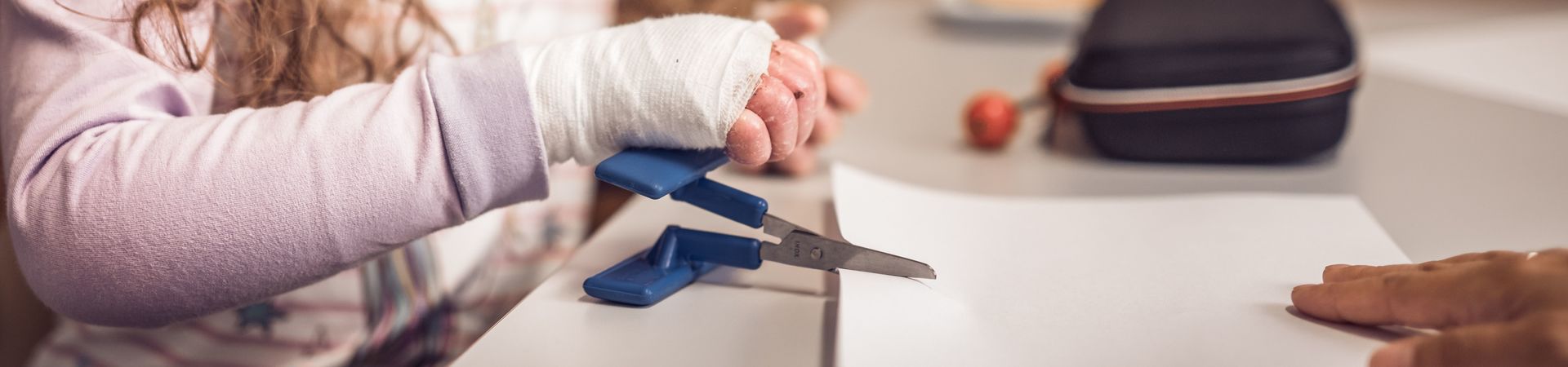 EB patient cuts a piece of paper with an adapted pair of scissor 