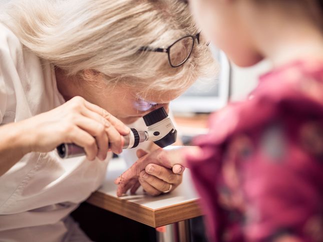 Ärztin untersucht Hand einer kleinen EB-Patientin 