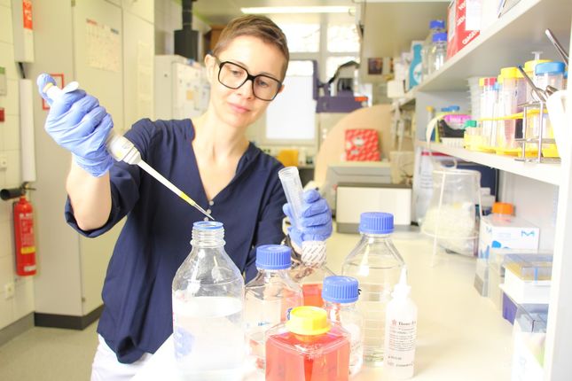 Junge Frau mit Brille bei Arbeit mit Pipette im Labor